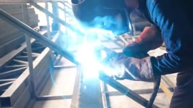 Mesleki güvenliğe dikkat eden kaynakçı, işçi atölyede kaynak yapıyor.