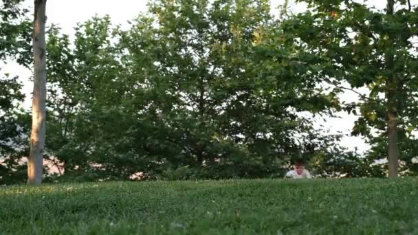 Бегущий мальчик, бегущий по траве, в парке — стоковое видео