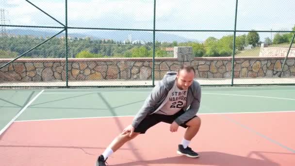 Паховые упражнения, человек делает паховые упражнения на баскетбольной площадке — стоковое видео