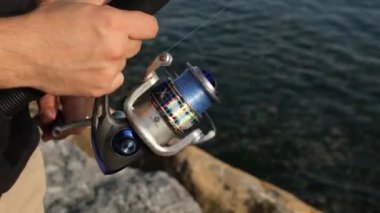 Balık oltası, bir adam balık makarasını deniz kenarına çevirir, yaklaş.