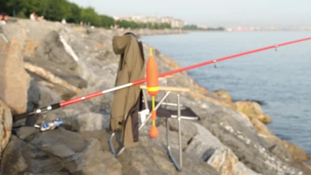 Balıkçı sandalyesi, balıkçı sandalyesi, şamandıra ve olta deniz kenarında. — Stok video