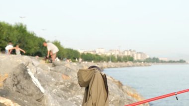 Balıkçı ve torun, yaşlı adam ve torun kayalıklarda balık avlıyorlar.