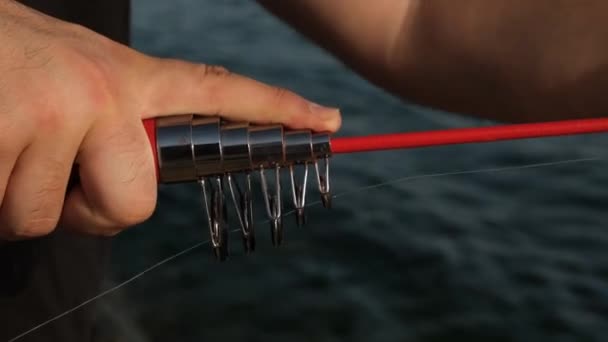 Vara de pesca, o homem está puxando uma vara de pesca com as mãos, close-up, ângulo — Vídeo de Stock