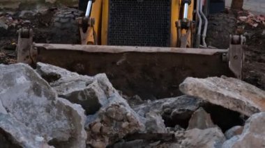 Mini kazıcı, mini kazıcı bir moloz yığını yakına topluyor.