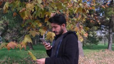 Kuru yaprak fotoğrafı, genç adam sonbaharda kuru yaprak fotoğrafı çekiyor.
