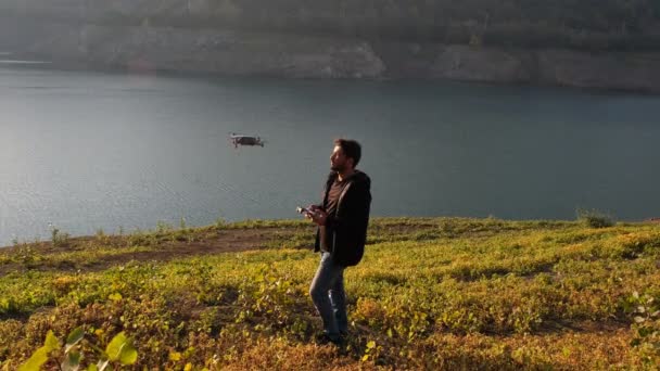 Opérateur de drone, opérateur de drone soulève drone avec la main et le pilote au-dessus du lac — Video