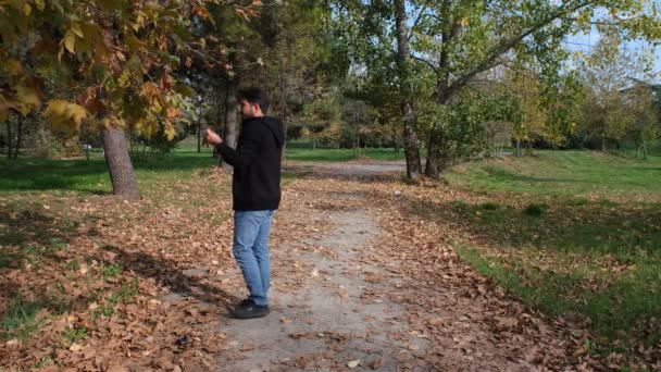 Telefonat, junger Mann telefoniert im Herbstpark — Stockvideo