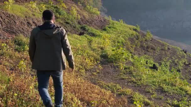 Человек походы, молодой человек походы по зеленой траве и возле озера — стоковое видео