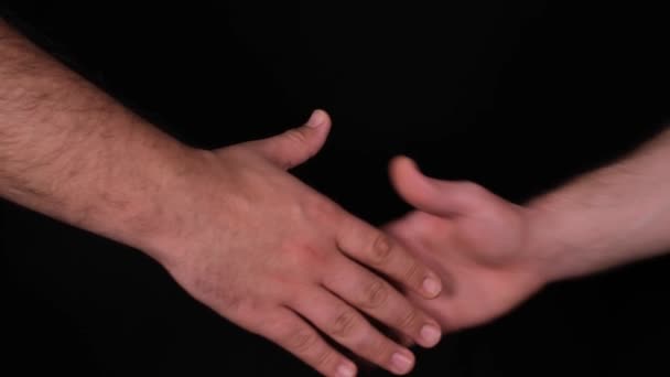 握手黒い背景で握手をする二人の男スローモーション — ストック動画