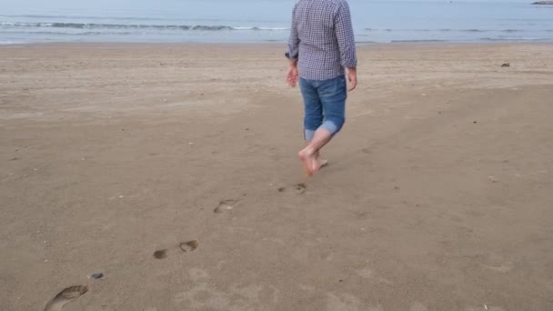 Huellas, el hombre caminando en las huellas de la playa se puede ver — Vídeos de Stock