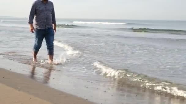 Spacerując morzem, mężczyzna w średnim wieku spaceruje po plaży jesienią — Wideo stockowe