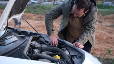 Adam araba motorunu kontrol ediyor