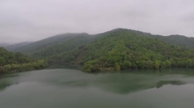 Göl, ağaçların önünde, göl yatağında ve göldeki yeşil tepelerin yansımasıyla.