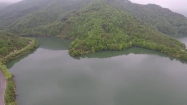  Ormanlık tepeler, gökyüzü görüntüsü yeşil orman tepeleri ve göl yansıması.