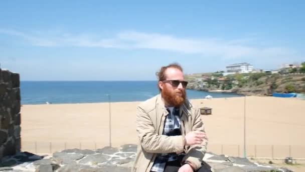 男人抽烟 高加索男人在岩石上的海滩上抽烟 — 图库视频影像