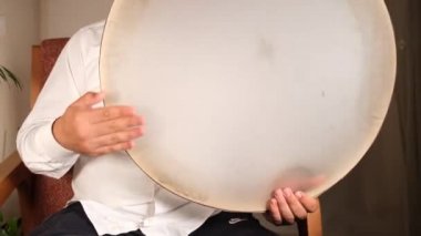 Beyazlı adam daf 'ı oynuyor.
