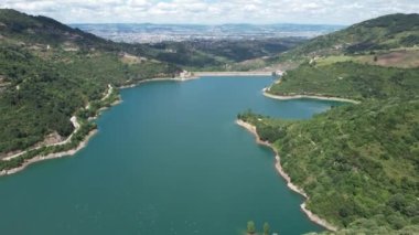 Aerial shot of potable water reservoir among green mountains