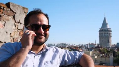 İstanbul 'da, Galata Kulesi' nde gözlüklü bir turist telefonla konuşuyor.