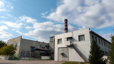 Atölyedeki bir boruyla sanayi bölgesinin görüntüsü, gökyüzüne karşı sanayi atölyeleri, sanayi bölgesi, sanayi bölgesinde binalar.