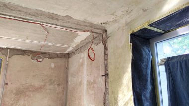 Dairenin yenilenmesi, tavan ve pencerenin görünümü, sıva duvarlar, boş oda, boş duvar, sıva duvar, odanın köşesi, kapı girişi, elektrik kablosu.