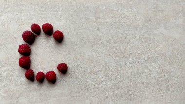 Ahududu harfi C harfi beyaz desenli bir masa, büyük ahududu böğürtlenleri, ahududu arka planı, yemek arkaplanı, mesaj için alan, dut mektubu, yiyecek mektubu.