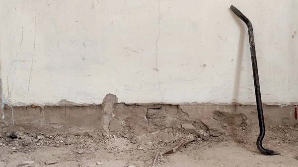 Widok Zniszczonej Białej Ściany Betonowej Złom Spoczywa Ścianie Narzędzie Budowlane — Zdjęcie stockowe