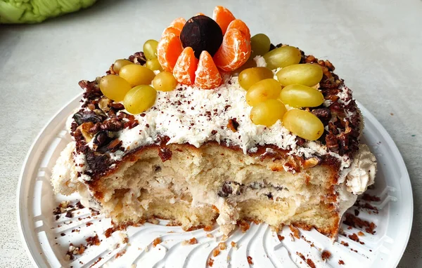 Birthday cake, homemade cake, pie in close-up, biscuit with nuts and fruits in cream on a white textured table, bitten cake