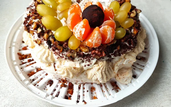 Birthday cake, homemade cake, pie in close-up, biscuit with nuts and fruits in cream on a white textured table, bitten cake