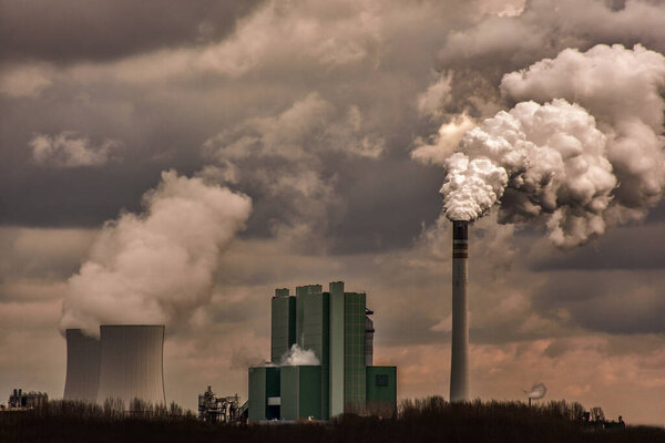Немецкий завод с дымоходом и большим количеством дыма и пара в облачный день