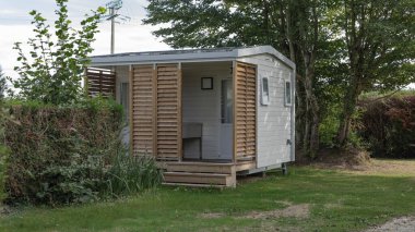 Üzerinde paslanmaz çelik lavabo olan küçük beyaz bir kulübe.