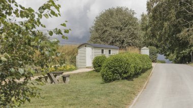 Üzerinde paslanmaz çelik lavabo olan küçük beyaz bir kulübe.