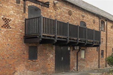 Eski bir ahır binasında, kırmızı tuğladan bir duvara karşı siyah boyalı balkon.