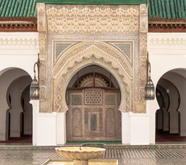 Yeşil kiremit çatılı ve ön planda bir çeşmesi olan geleneksel Fas kapı girişinin süslü taşı ve fayansı.