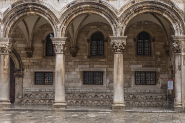 Dubrovnik şehrinde bal rengi taşlar ve bir dizi kemer yolundan yapılmış kadim süslü bir bina.