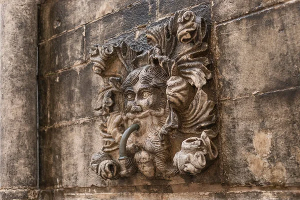 Ancient wall plaque of a face with lead fountain pipe Dubrovnik made out of carved honey coloured stone