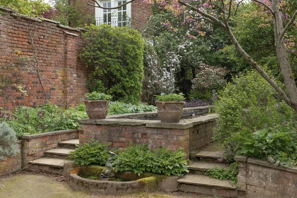 Garden scene with steps and red brick walls in the season of spring with the shrubs and plants just starting to come to life