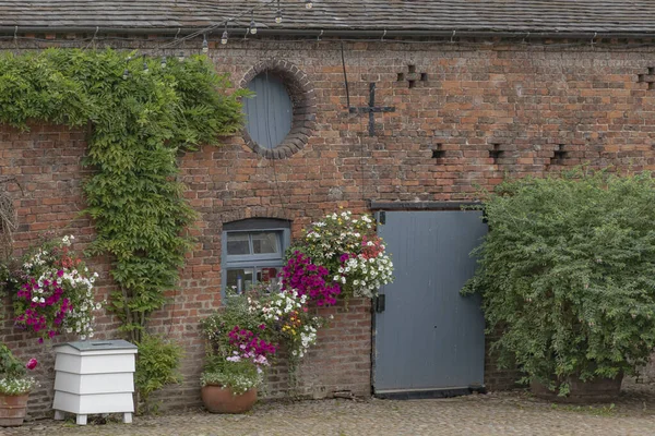 The side of a barn with round window and beehive waste bin painted white