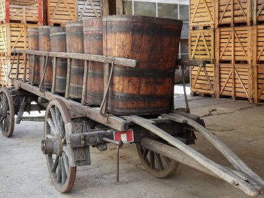  old wooden cart with wooden crates to hold wine bottles in the background         