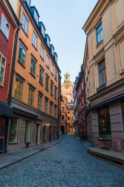 Stora Gramunkegrand Sokağı 'ndaki tarihi binaların ve kışın gün batımında Aziz Nicholas Kilisesi' nin kulesinin manzarası Stockholm, İsveç