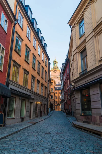 Stora Gramunkegrand Sokağı 'ndaki tarihi binaların ve kışın gün batımında Aziz Nicholas Kilisesi' nin kulesinin manzarası Stockholm, İsveç