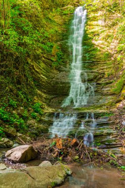 High waterfall in the park Berendeyevo Tsarstvo in sunny summer day, Sochi, Russia