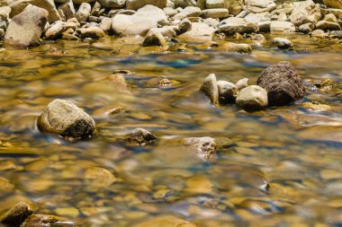 Long exposure photo of the river flowing in rocky ravine in sunny day