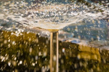 A fountain tube with a jet of water escaping from it closeup