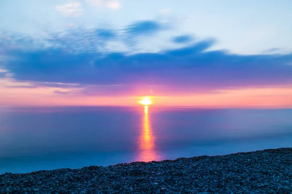 海の上の日没の背景にある小石のビーチの長い露出ビュー — ストック写真