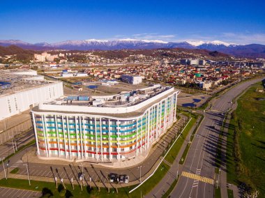 Adler, Sochi, Russia - December 9, 2017: Drone view of apartment buildings at Triumphal street on the background of ridge of mountains in sunny day