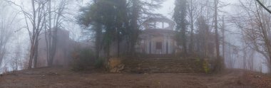 Panoramic view of the abandoned building of the former restaurant on the top of Mount Akhun in dense fog, Sochi, Russia