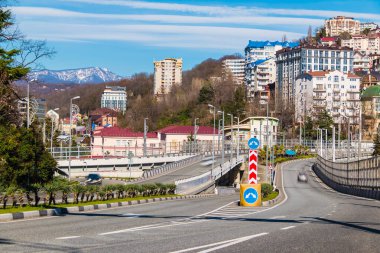 Güneşli bir günde Kurortny Prospekt ile dağların ve apartmanların arka planında yer alan şehir manzarası, Sochi, Rusya