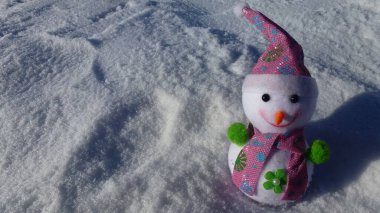 Snowman in a pink cap on a background of snow