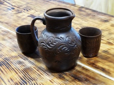 Tahta bir masada gözlüklü seramik sürahi. Şarap, kvass veya komposto için seramik seti.                               