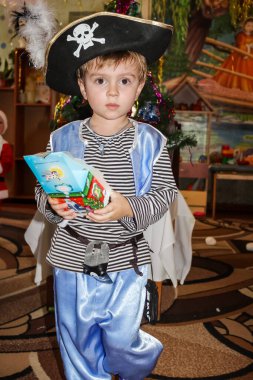 Korsan gibi giyinmiş küçük bir çocuk ve yeni yıl hediyesi. 